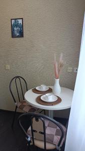een witte tafel met twee stoelen en een vaas erop bij 2 комнатная квартира в центре города in Karagandy
