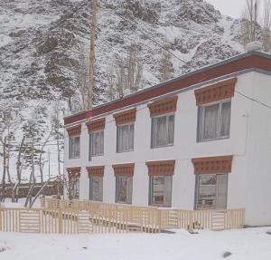 a white building with a snow covered mountain at Norbooling HomeStay, Leh Ladakh in Leh