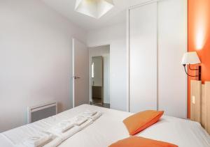 a bedroom with a white bed with an orange pillow at Cosy plage - Appt climatisé avec piscine partagée in Sète +15 photos