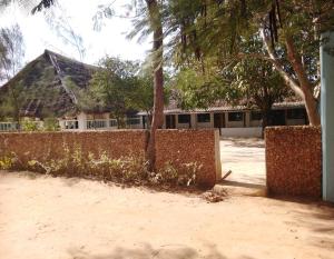 a fence and trees in front of a building at Subira Guest House and Restaurant in Lamu