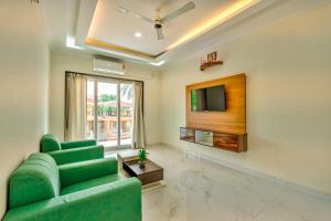 uma sala de estar com um sofá verde e uma televisão em Greenfinch Apartment em Baga