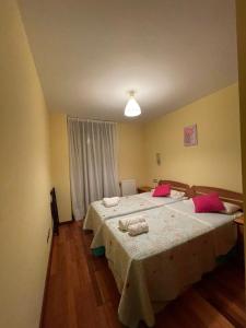 a bedroom with two beds with pink pillows at El Mirador de Llaneces 24A02 in Arenas de Cabrales