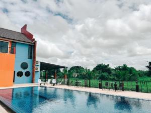 einen Pool mit Tischen und Stühlen neben einem Gebäude in der Unterkunft Tuscany Hotel Buriram in Buriram