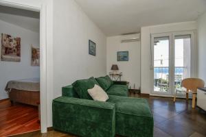 a living room with a green couch and a bed at Trstenik Beach Apartment in Split