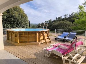 a deck with a pool and two chairs and a table at Rez de Villa au calme piscine chauffée, terrain pétanque in Vidauban