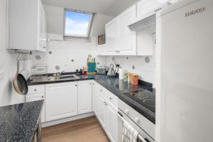 a kitchen with white cabinets and black counter tops at Beautiful 1 bedroom apartment with free on street parking in Oban