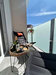 un balcón con una mesa con botellas de vino y una silla en Sol, playa y relax en Fuengirola en Fuengirola