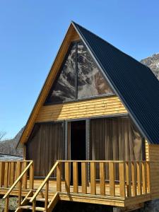 une cabine avec un toit en gambrel et une terrasse dans l'établissement Sunny Side Cottage, à Kazbegi