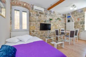 1 dormitorio con cama y pared de piedra en Casa Matošića Apartments, en Split