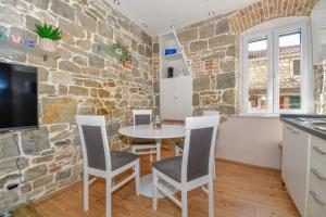 cocina con mesa, sillas y pared de piedra en Casa Matošića Apartments, en Split