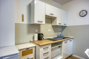 una pequeña cocina con armarios blancos y fregadero en Apartments Jantar - Happy Rentals en Novo Mesto