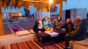 a group of people sitting around a table with drinks at Horaz Merzouga Camp in Merzouga