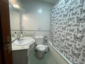 uma casa de banho com WC e um lavatório com borboletas na parede em Apartamento Buenaventura em Chiclana de la Frontera