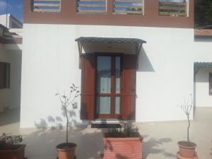 uma porta da frente de uma casa branca com vasos de plantas em Domo Serra E Mesu em Magomadas