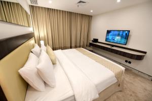 een slaapkamer met een groot wit bed en een flatscreen-tv bij Carlton Tower Hotel Kuwait in Koeweit