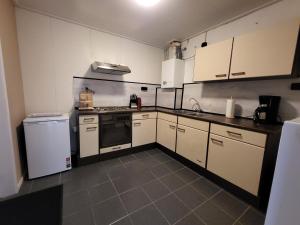 a kitchen with white cabinets and a stove and refrigerator at vakantie appartement Stadskanaal in Stadskanaal