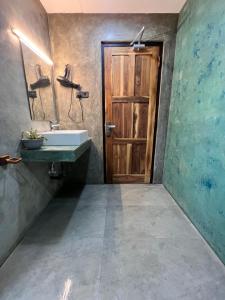 een badkamer met een wastafel en een houten deur bij Roy's Villa in Sigiriya