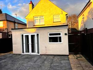 a small white garage with a yellow house at 4 Bedroom House near City Centre with Parking in Gloucester