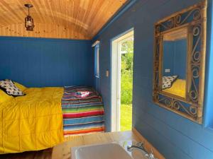 a bedroom with a bed with a mirror and a sink at Shepherds Hut - Brecon Beacons in Llangadog
