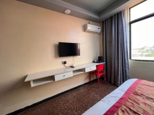 Habitación de hotel con escritorio, TV y cama en EASTERN PLAZA HOTEL en Yuba