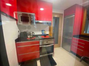 eine rote Küche mit einem Herd und einer Mikrowelle in der Unterkunft Apartamento Villa Termal Mondariz Balneario in Mondariz-Balneario