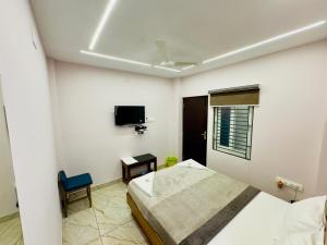 a bedroom with a bed and a tv on the wall at GREENS INN in Chennai