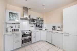 a white kitchen with white cabinets and appliances at River View 2 Bed 2 Bath Flat - London City Airport, Excel, Pontoon Dock in London