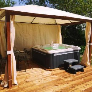 - un bain à remous installé sous une tente sur une terrasse en bois dans l'établissement Doubs Moment, 