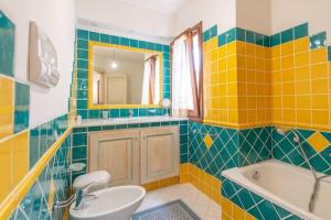 ein Badezimmer mit gelben und blauen Fliesen sowie einer Badewanne und einem Waschbecken in der Unterkunft Villa Zagara in Olbia