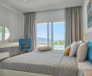 een slaapkamer met een groot bed en een blauwe stoel bij Lefkimmiatis Villas Corfu in Afionas