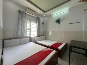 a room with two beds and a desk and a window at SPOT ON 899 Bao Ngan in Da Nang