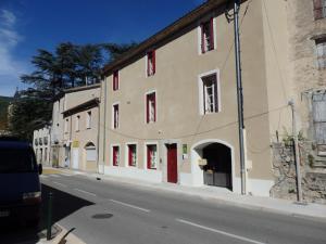 un edificio con puertas rojas en el lateral de una calle en Le Merlanson chambres d'hôtes, en Bez-et-Esparon