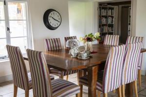 a dining room table with chairs and a clock on the wall at Fabulous Farmhouse in Hampshire in London