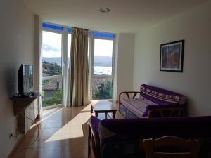 a living room with a couch and a tv and windows at APARTAMENTOS CANADA 2 in Raxó