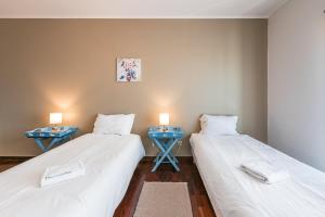 2 Betten in einem Zimmer mit 2 blauen Tischen in der Unterkunft GuestReady - Espinho Beach Flat in Espinho