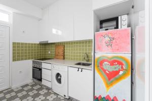 eine Küche mit einem Kühlschrank und einem Gemälde darauf in der Unterkunft GuestReady - Ílhavo Divine Encounters in Ílhavo