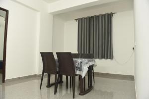 Sai Homestay Panaji 2 BHK and Studio Apartment في باناجي: طاولة طعام مع كراسي وستارة