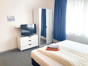 um quarto de hotel com uma cama e uma televisão em Haus Hanseatic em Helgoland