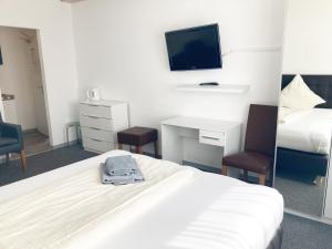 um quarto de hotel com uma cama, uma secretária e uma televisão em Haus Hanseatic em Helgoland