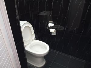 a bathroom with a toilet with a black tiled wall at Cozy Apartment with Pool & 10 mins walk to Beach in Mont Choisy