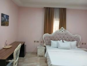Schlafzimmer mit einem großen weißen Bett und einem Schreibtisch in der Unterkunft Agoms Hotel 