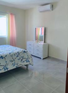 a bedroom with a bed and a dresser with a tv at Sunset Home 2B (Gated) in Higuey