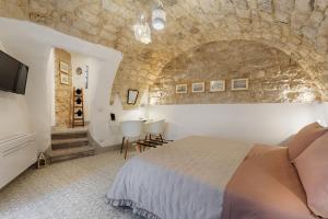 a bedroom with a bed and a stone wall at Vico Prato 1, gocce di Sicilia in Ragusa