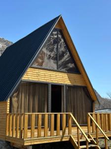 a cabin with a gambrel roof and a deck at Sunny Side Cottage in Stepantsminda