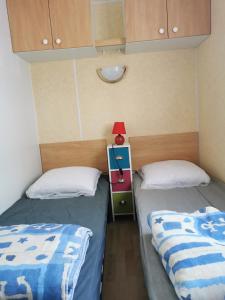 a bedroom with two beds and a red lamp on a night stand at Mobile Home La Tranche sur Mer 6 personnes in Angles