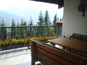 eine Holzbank auf einem Balkon mit Blumen in der Unterkunft Semmering Villa Sonnenschein in Semmering