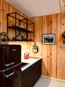 uma cozinha com paredes de madeira e um frigorífico preto em Przyjedź Tutaj em Maków Mazowiecki