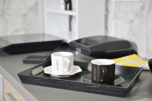 twee koffiekopjes op een dienblad op een aanrecht bij Reina Apartments Skopje in Skopje