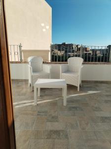 2 chaises blanches et un banc sur un balcon dans l'établissement Antico Centro Quartu B&B, à Quartu SantʼElena