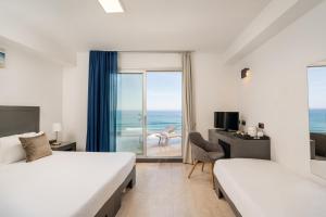 a hotel room with two beds and a view of the ocean at Bellevue Sardinia Resort, Affiliated by Meliá in Valledoria